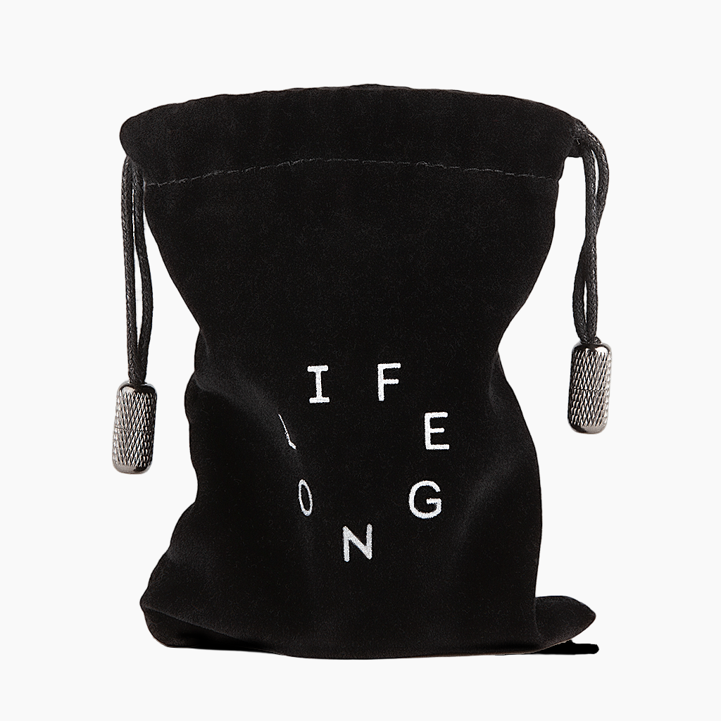 Black travel bag for refillable deodorant  from the brand Lifelongdeo. Bag is velvet with a circle white logo saying Lifelong. The straps has knurled metal details in the ends. 