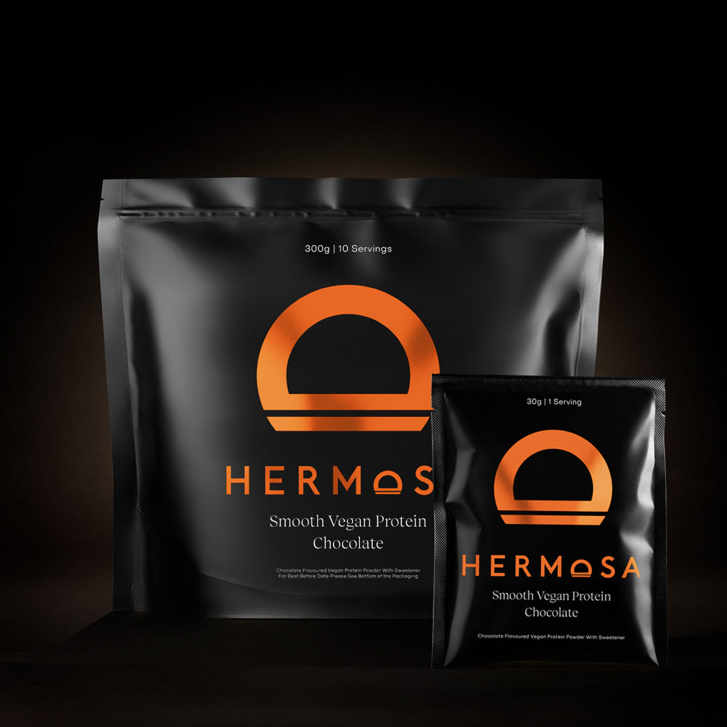 Two packages of Hermosa Smooth Vegan Protein Chocolate on a dark background