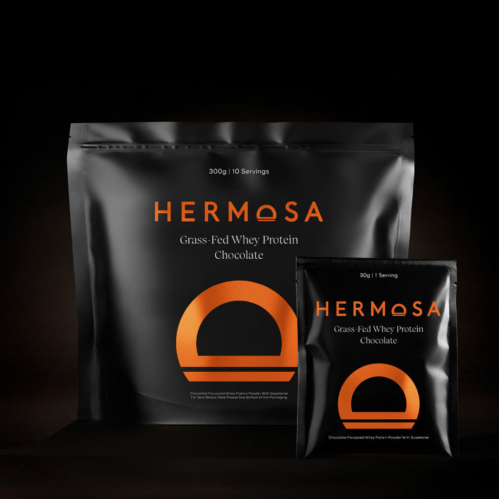 Hermosa Grass-Fed Whey Protein Chocolate packaging on a dark background