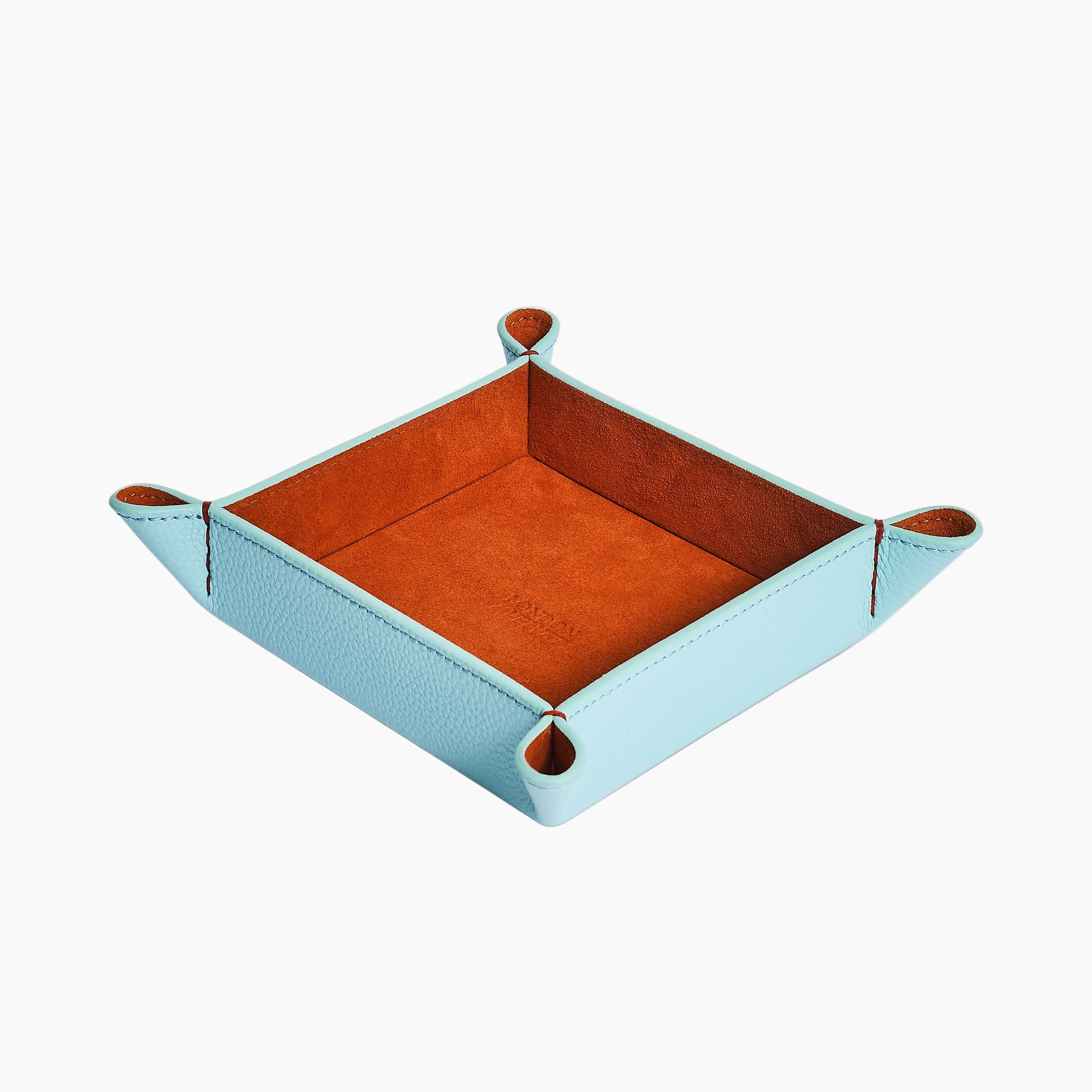 A square leather tray in light blue with a contrasting orange-brown interior, shown on a clean white background.