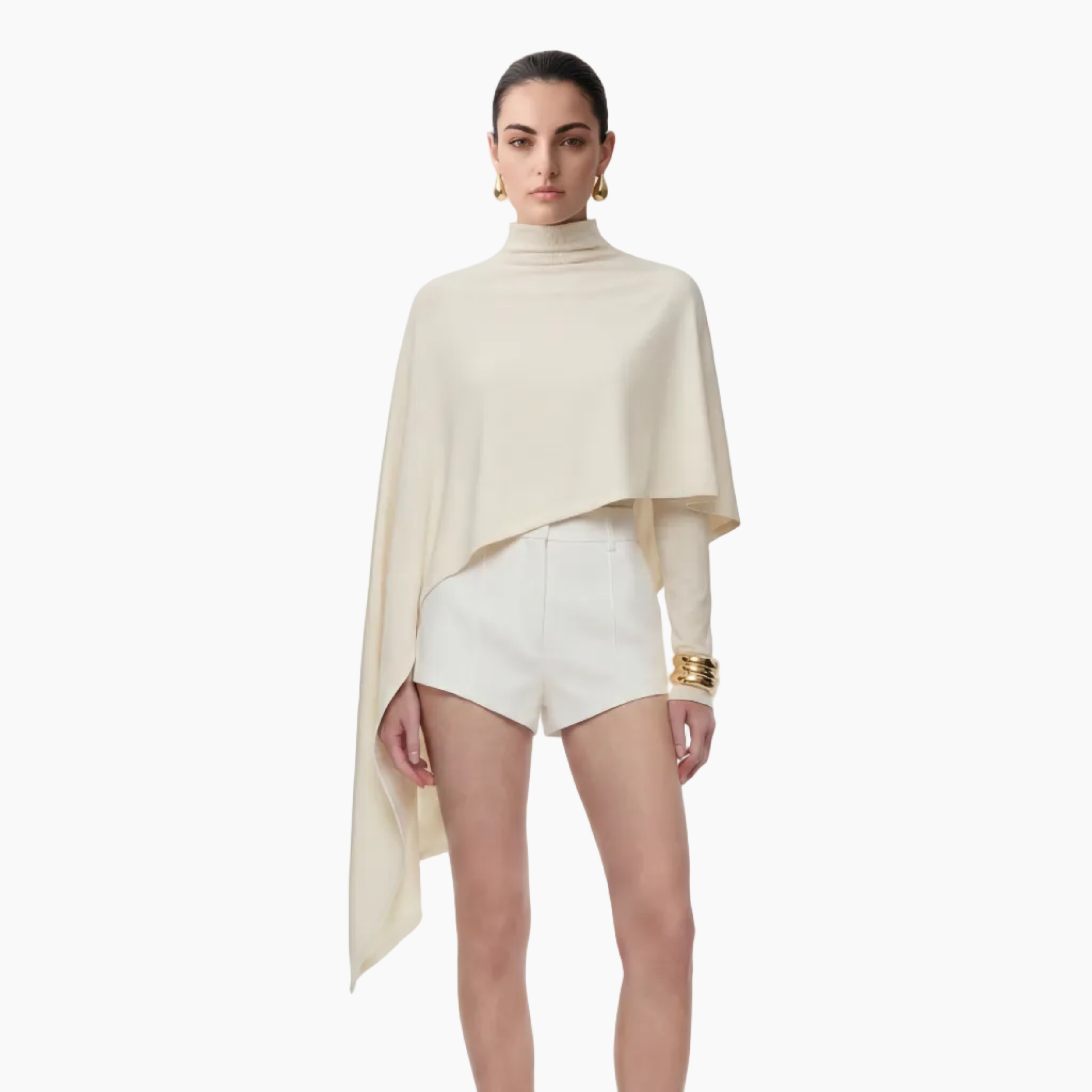 Woman wearing a beige poncho over a white outfit on a white background