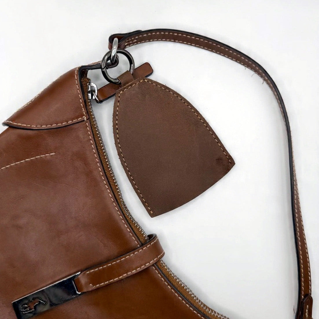 Brown leather bag with strap and visible brand logo on a white background