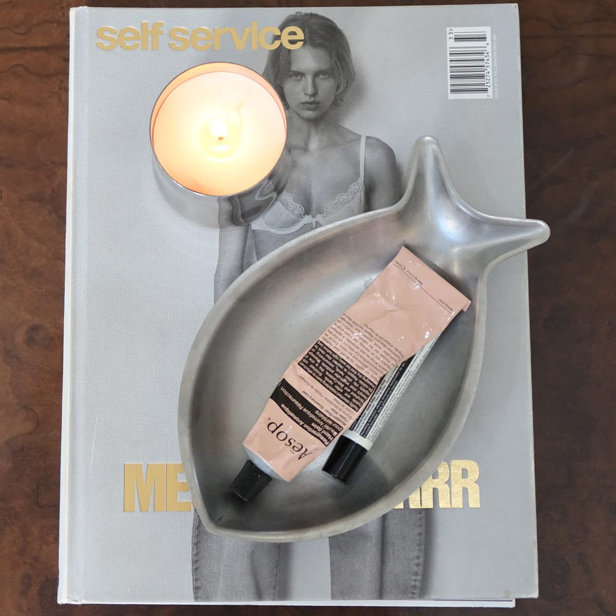 Magazine with a candle and cosmetic product on a wooden surface