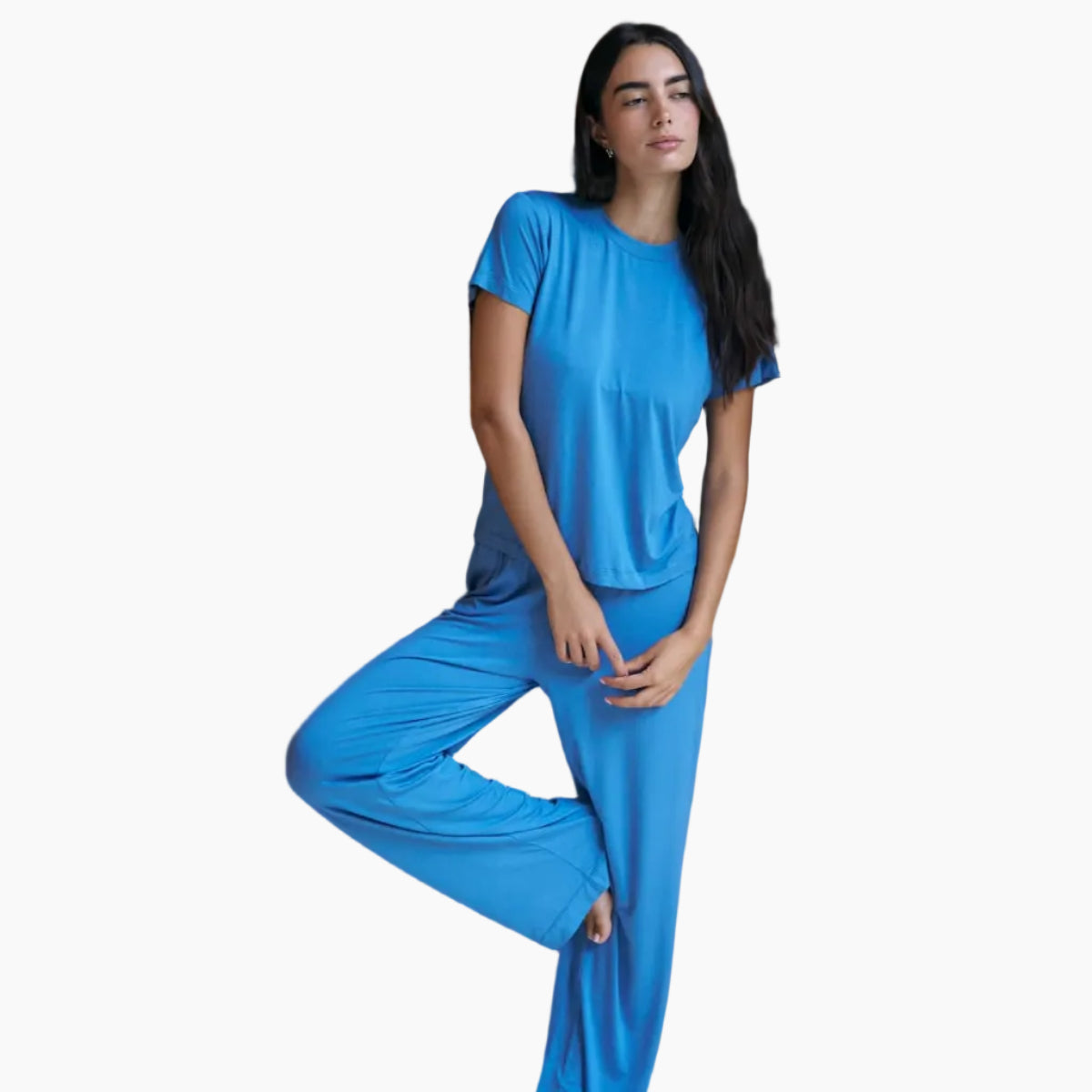 Woman in blue pajama set standing in a room with wooden shelves.