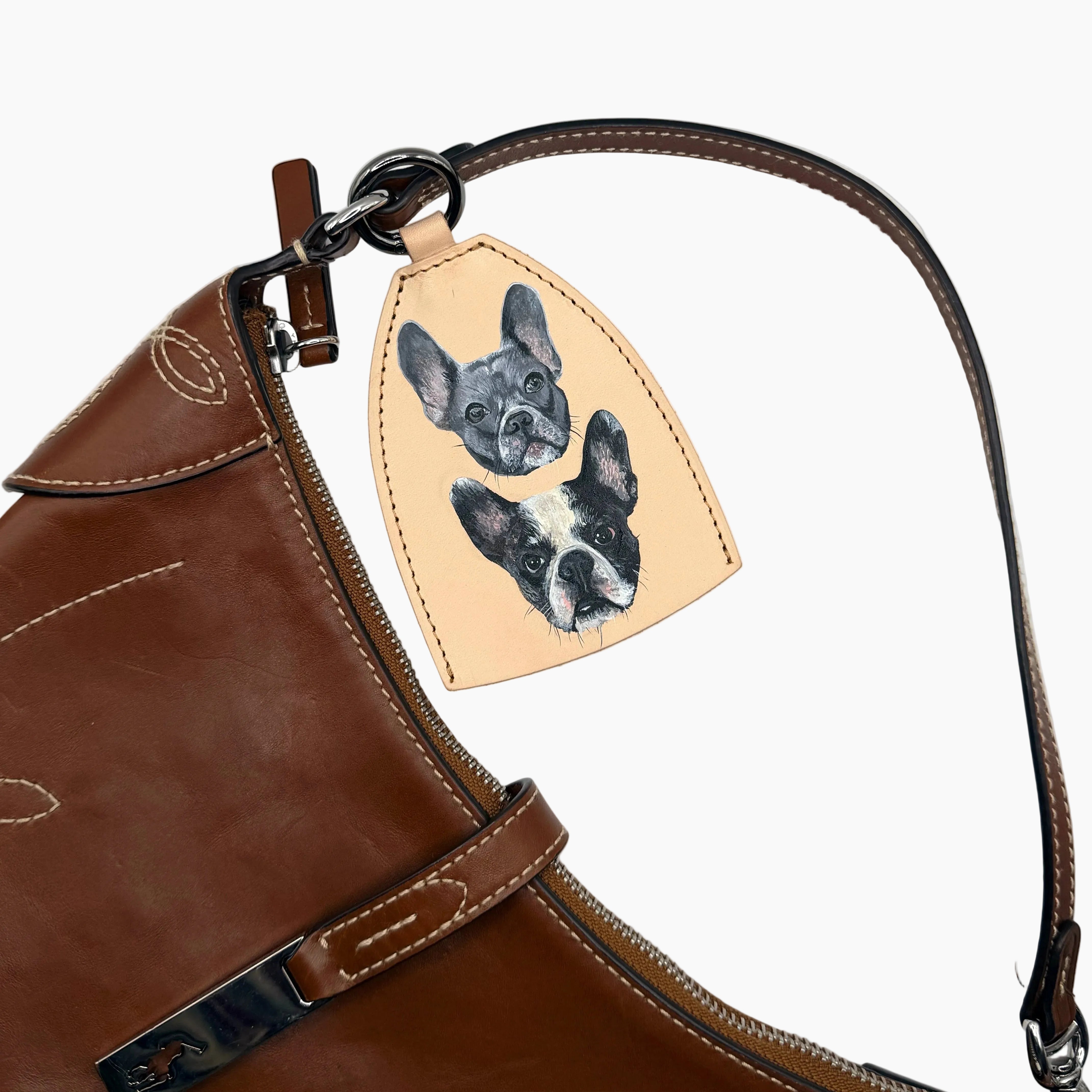 Brown leather bag with a dog-themed leather tag on a white background
