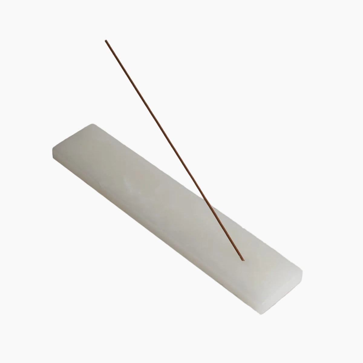 Incense stick on a white rectangular base against a beige background