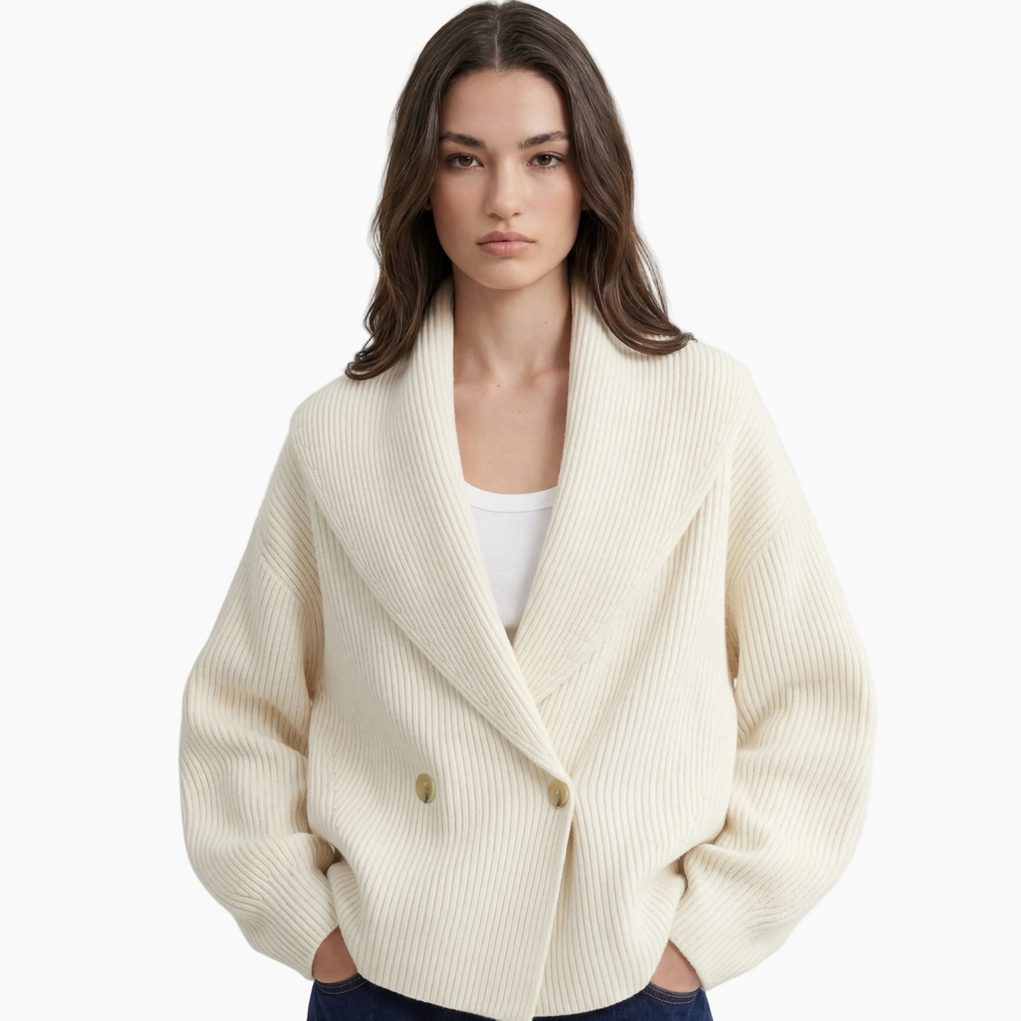 Woman wearing a cream-colored cardigan over a white top and blue jeans on a light gray background