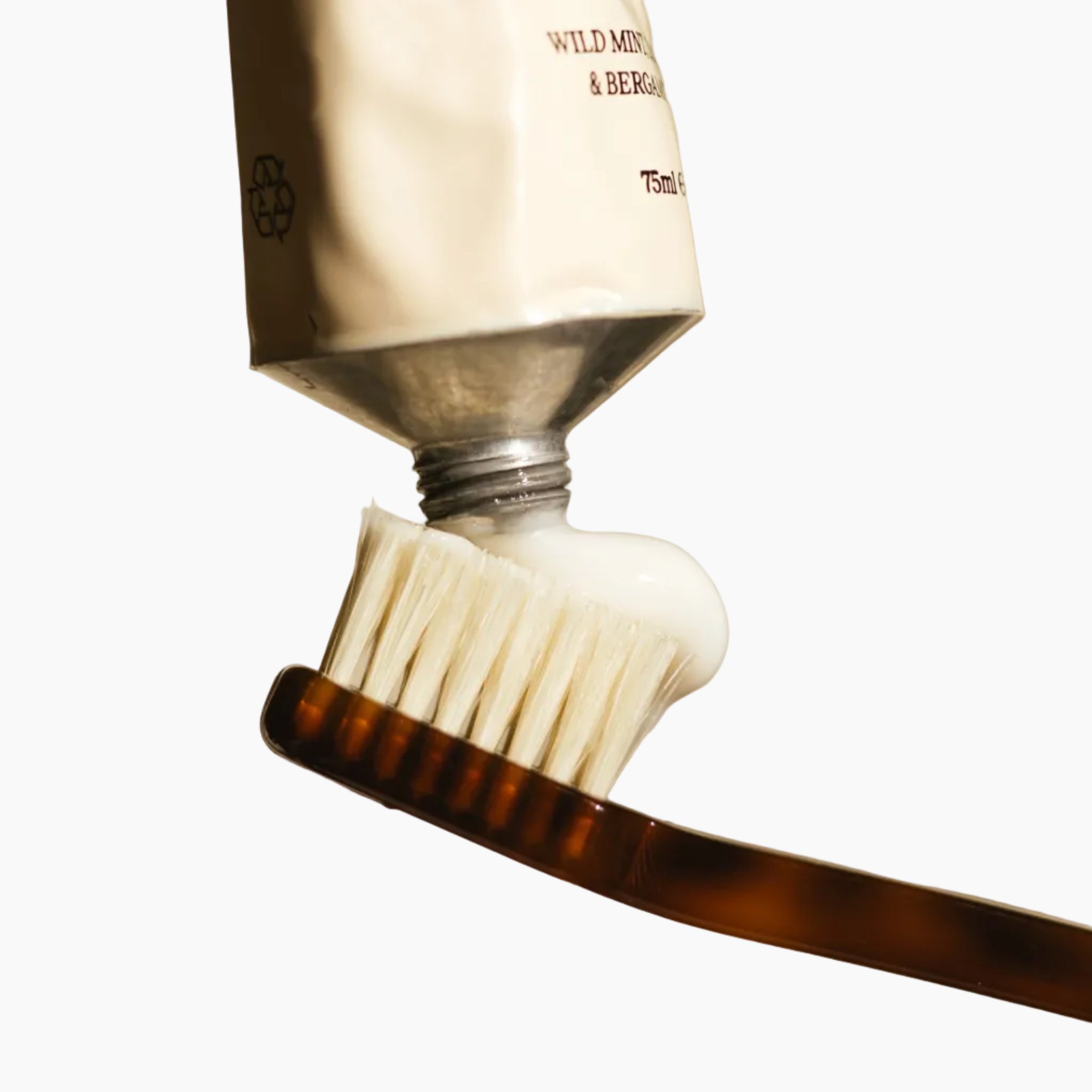 Toothbrush with toothpaste being applied on a beige background