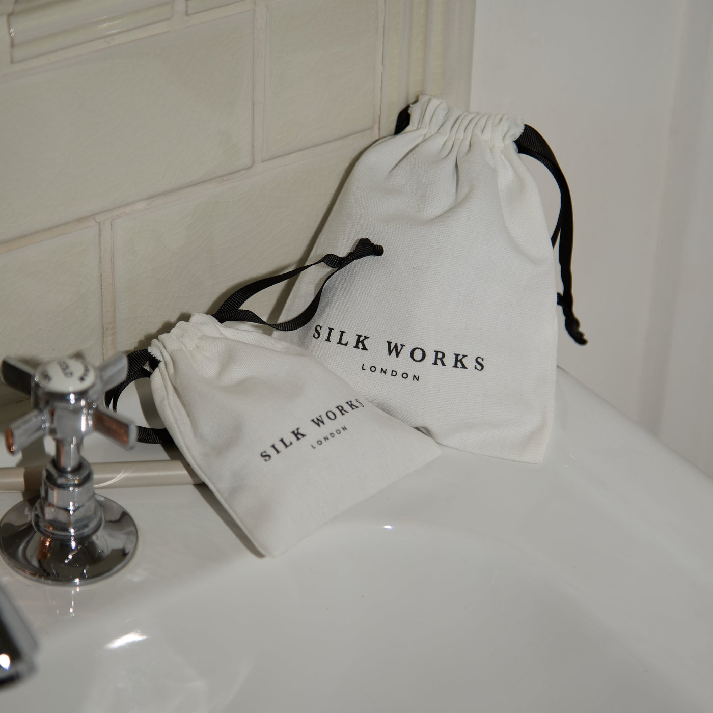 Two white drawstring bags with 'Silk Works London' branding on a white surface.