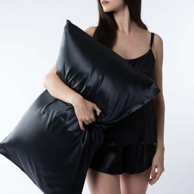 Woman wearing Silk Works black silk cami set holding a black silk pillowcase – Silk Works luxury sleep essentials