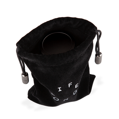 Black travel bag for refillable deodorant  from the brand Lifelongdeo. Bag is velvet with a circle white logo saying Lifelong. The straps has knurled metal details in the ends. You can see the deodorant in the bag.
