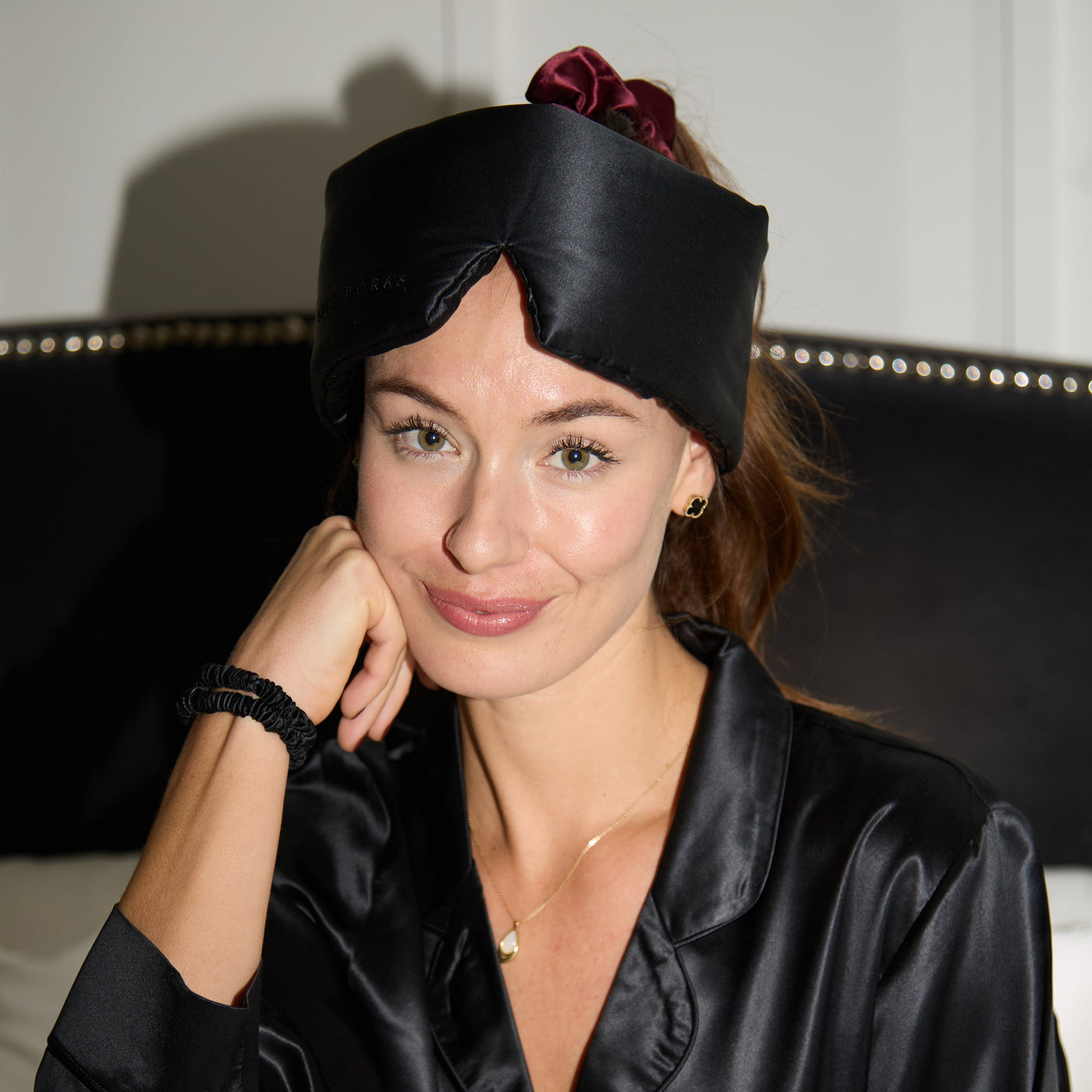 Woman wearing a black silk robe and eye mask indoors.