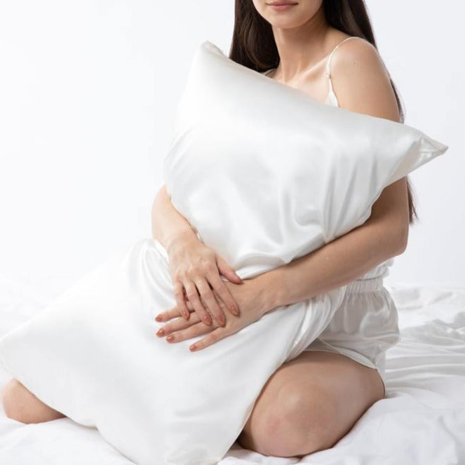 Lady wearing white silk camisole holding ivory silk pillowcase