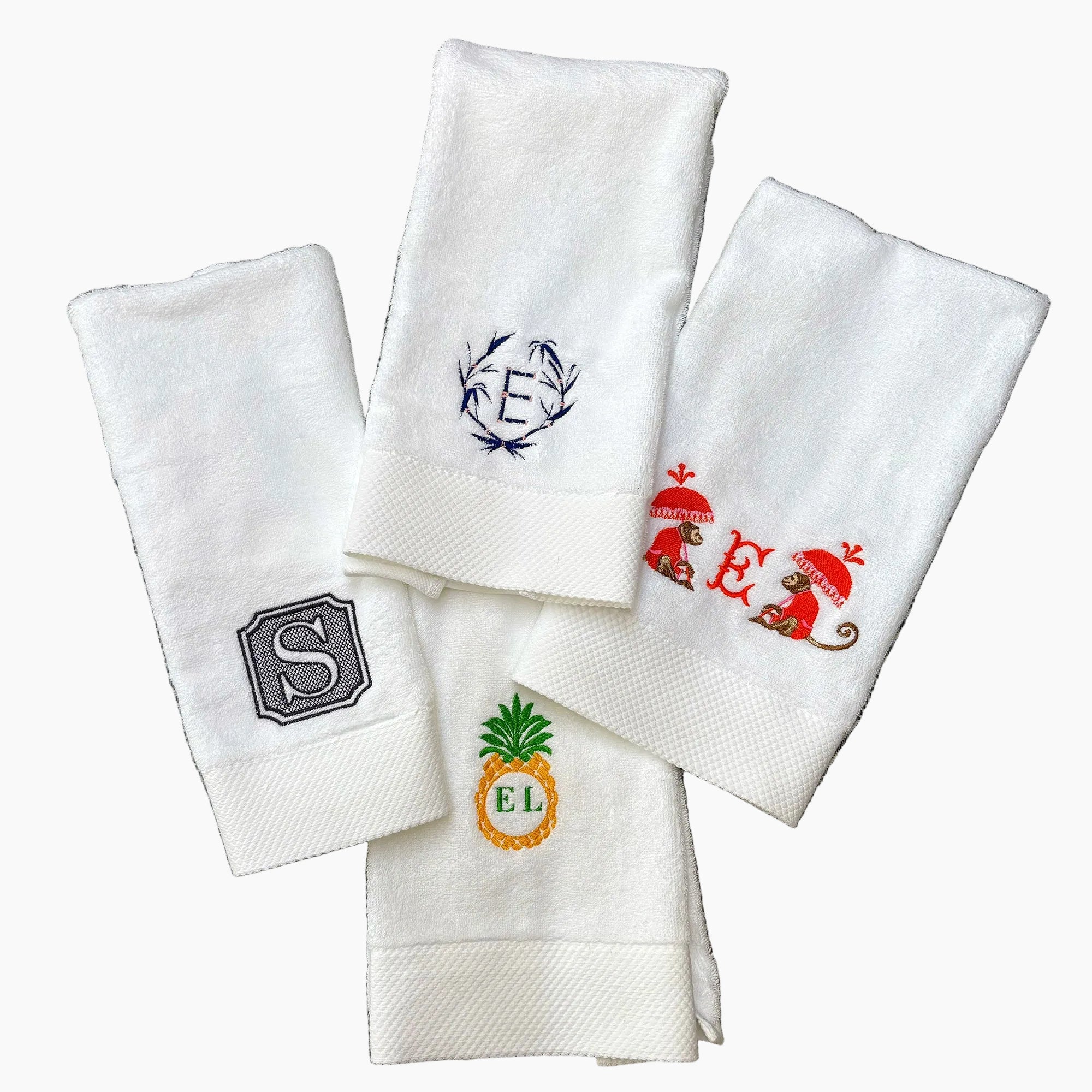 Set of white towels with embroidered monograms and designs on a textured surface