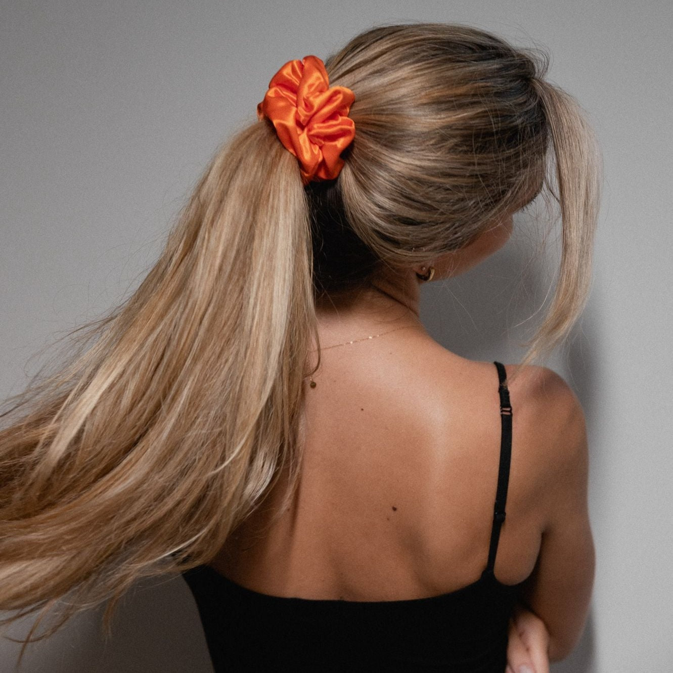 Lady with her long hair tied up in a bright orange large mulberry silk scrunchie.