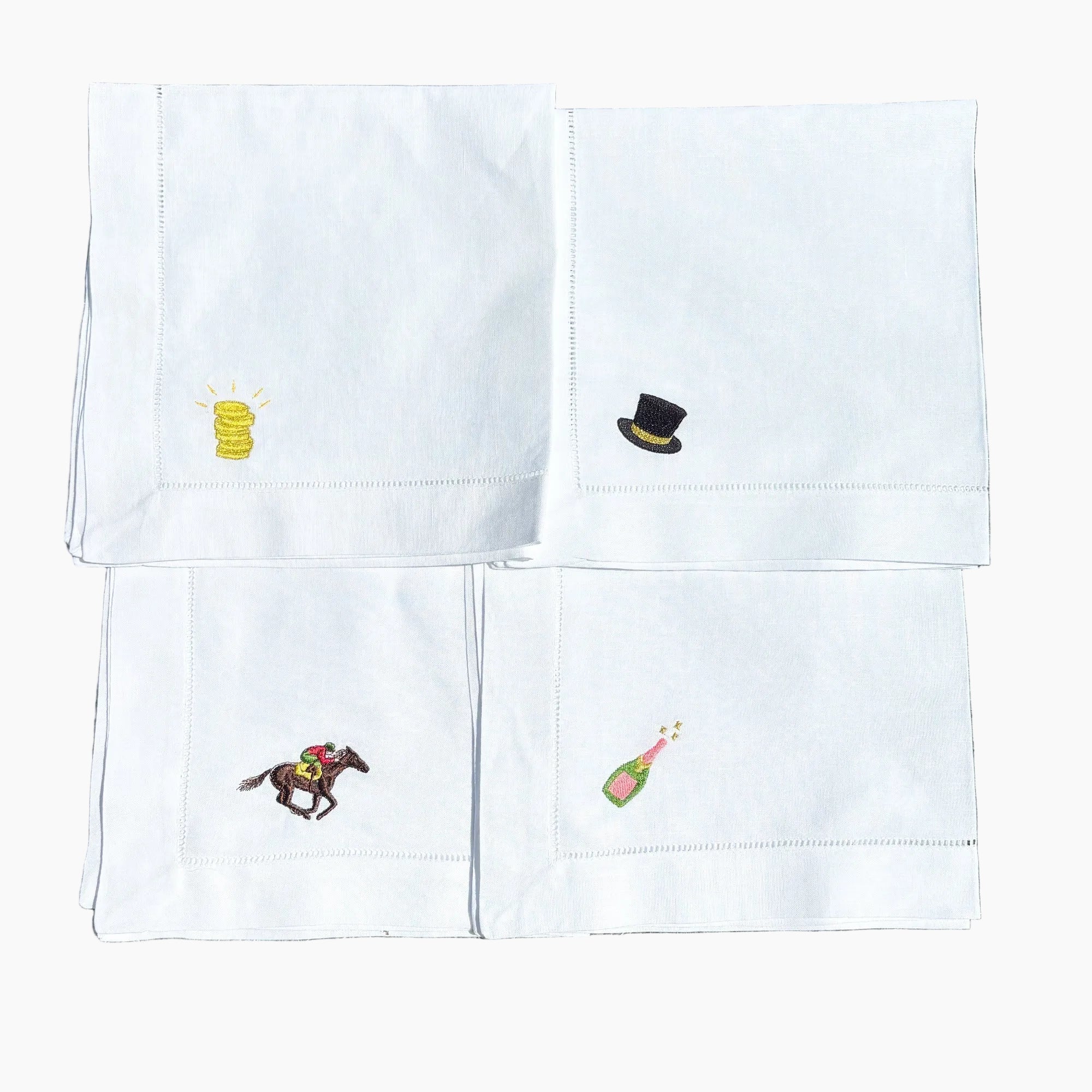 Set of white napkins with embroidered designs on a grass background