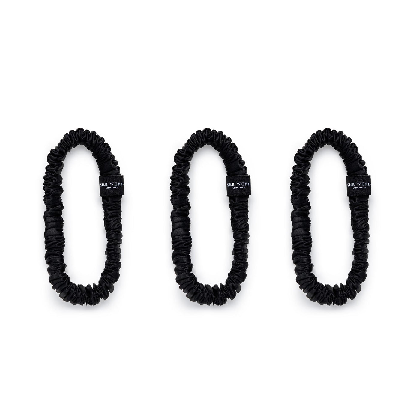 Trio of black 100% mulberry silk skinny scrunchies by Silk Works, designed to reduce breakage and frizz.