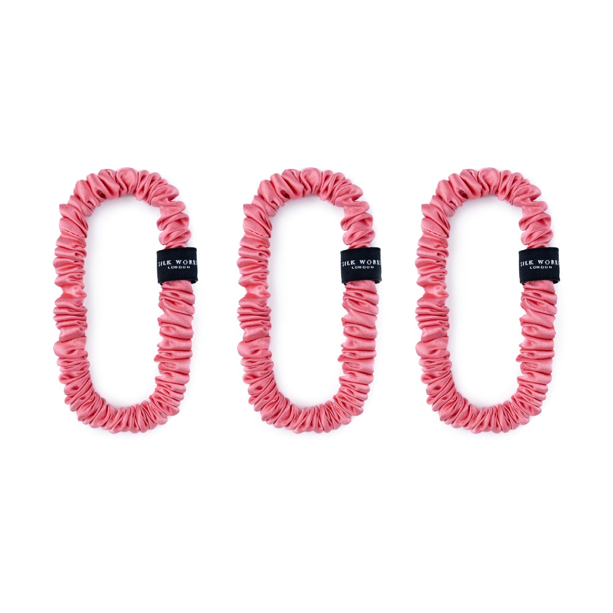 Trio of watermelon pink 100% mulberry silk skinny scrunchies by Silk Works, designed to reduce breakage and frizz.
